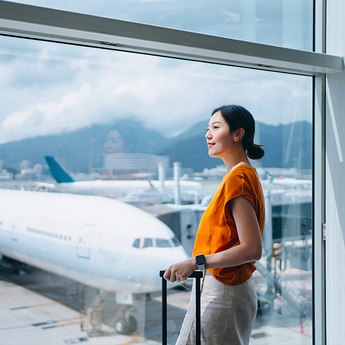 Fluggast schaut am Flughafen aus dem Fenster auf Start und Landebahn