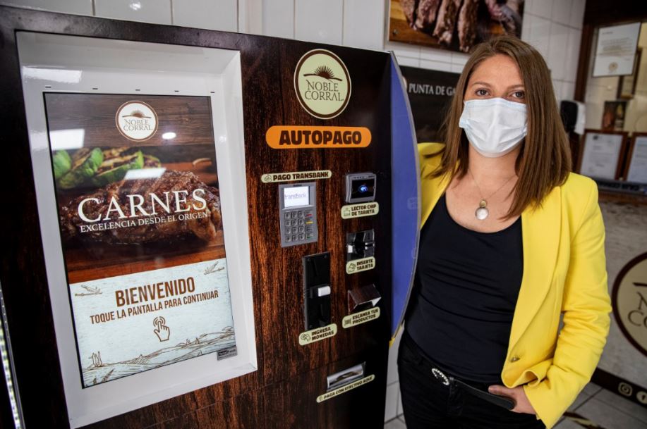 Una mujer con cubrebocas frente a un sistema de autopago de carnes