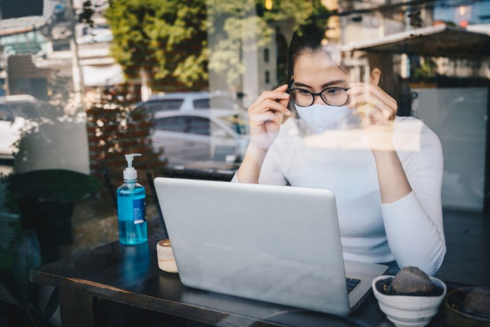 Una mujer con cubrebocas usa una laptop