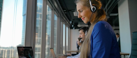 Mujer con audífonos frente a una laptop