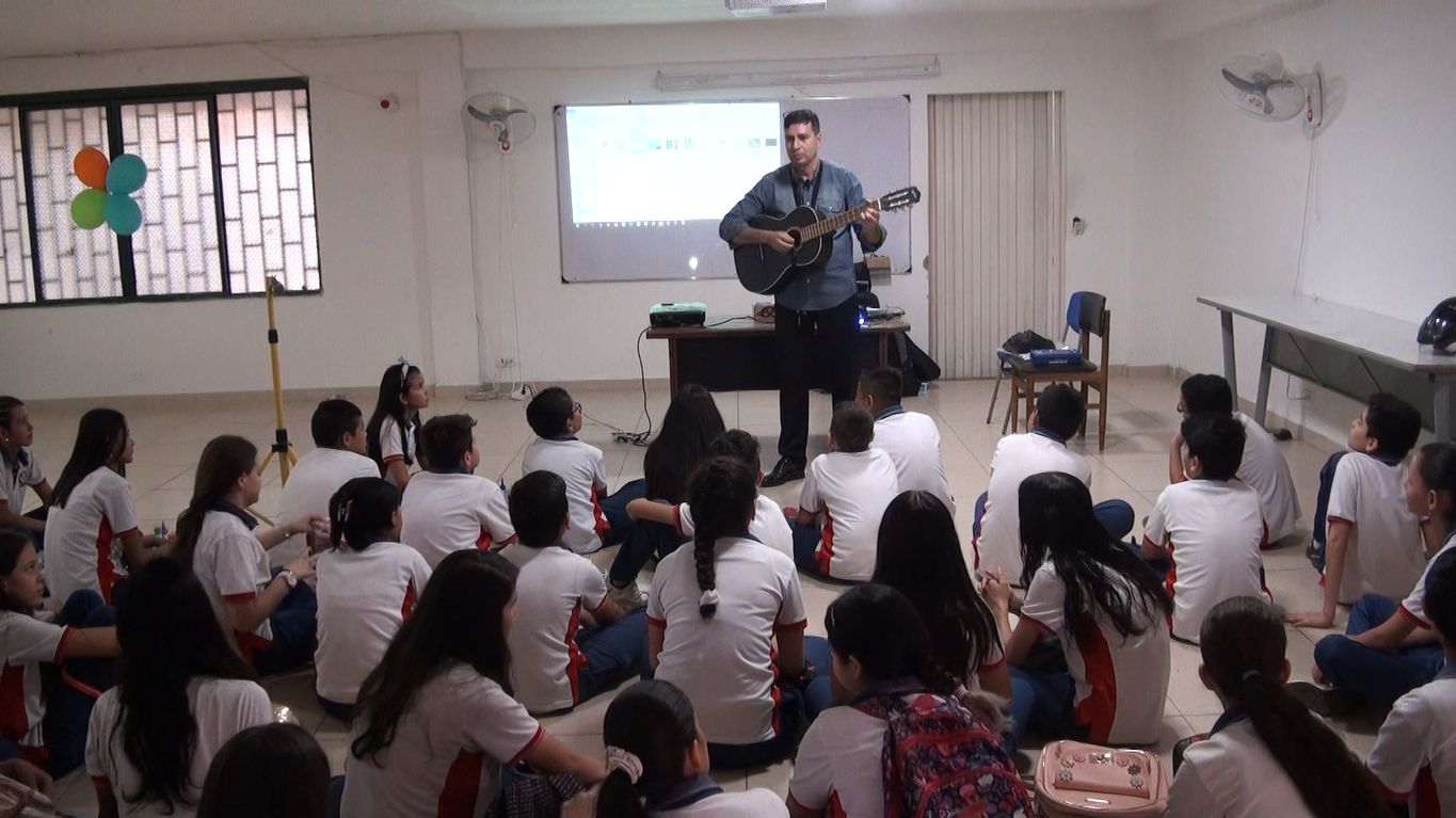 Hombre toca la guitarra frente a niños