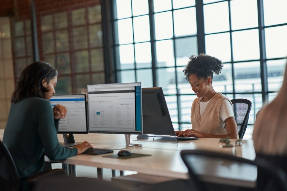 Dos mujeres trabajan en sus computadoras