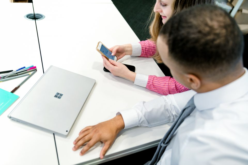 Dos personas trabajan en un teléfono móvil y una laptop