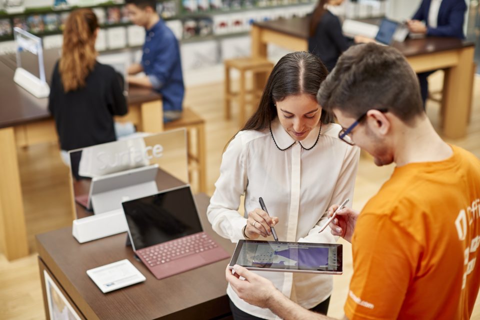 Vendedor mostra um notebook para uma cliente na loja.