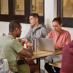 três pessoas em volta de uma mesa com laptop aberto