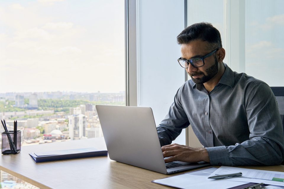 Homem sentado trabalha digitando em um notebook