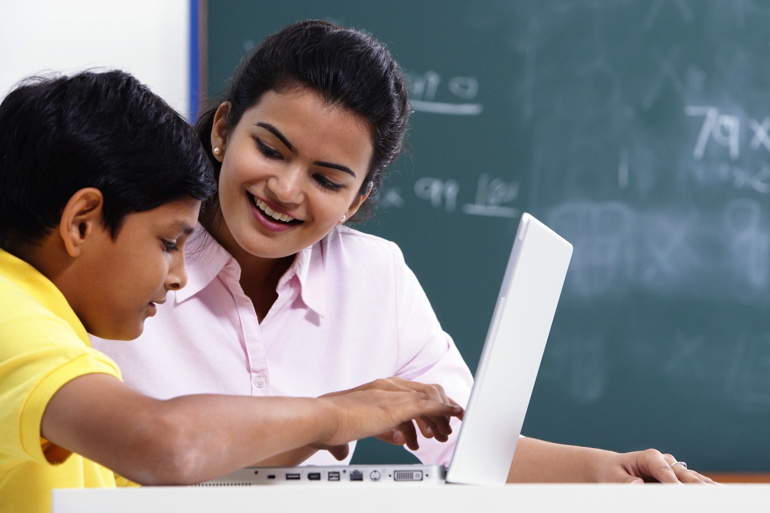 A teachers and student look at a laptop