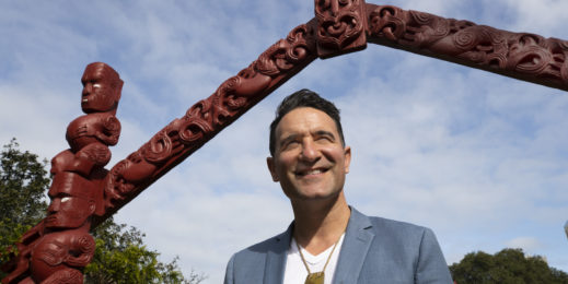 Man stand under Maori carved arch