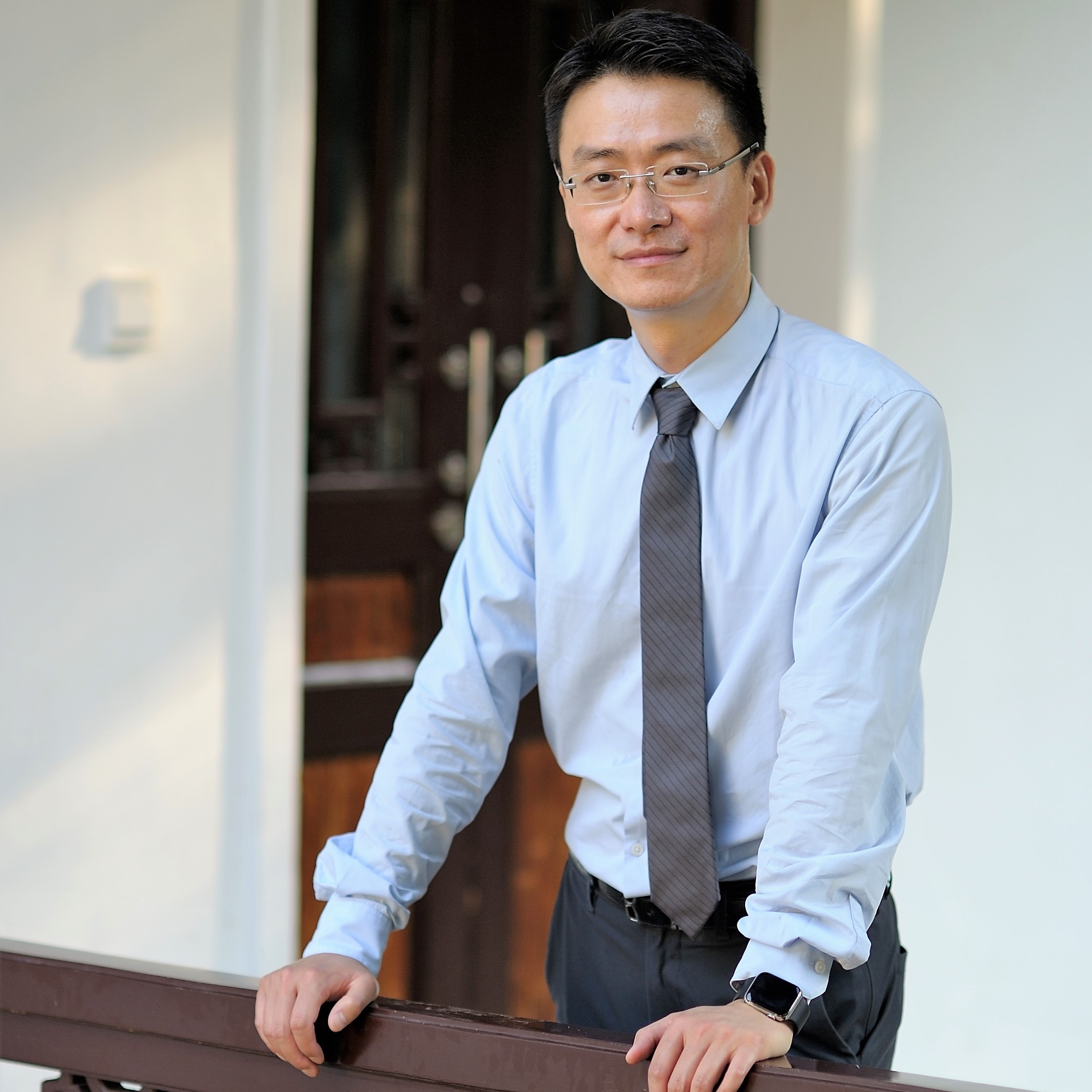 A man wearing a tie leans on a railing.