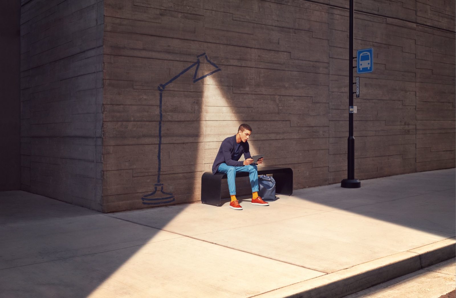 A man sits undera spotlight looking at a device in his hand.