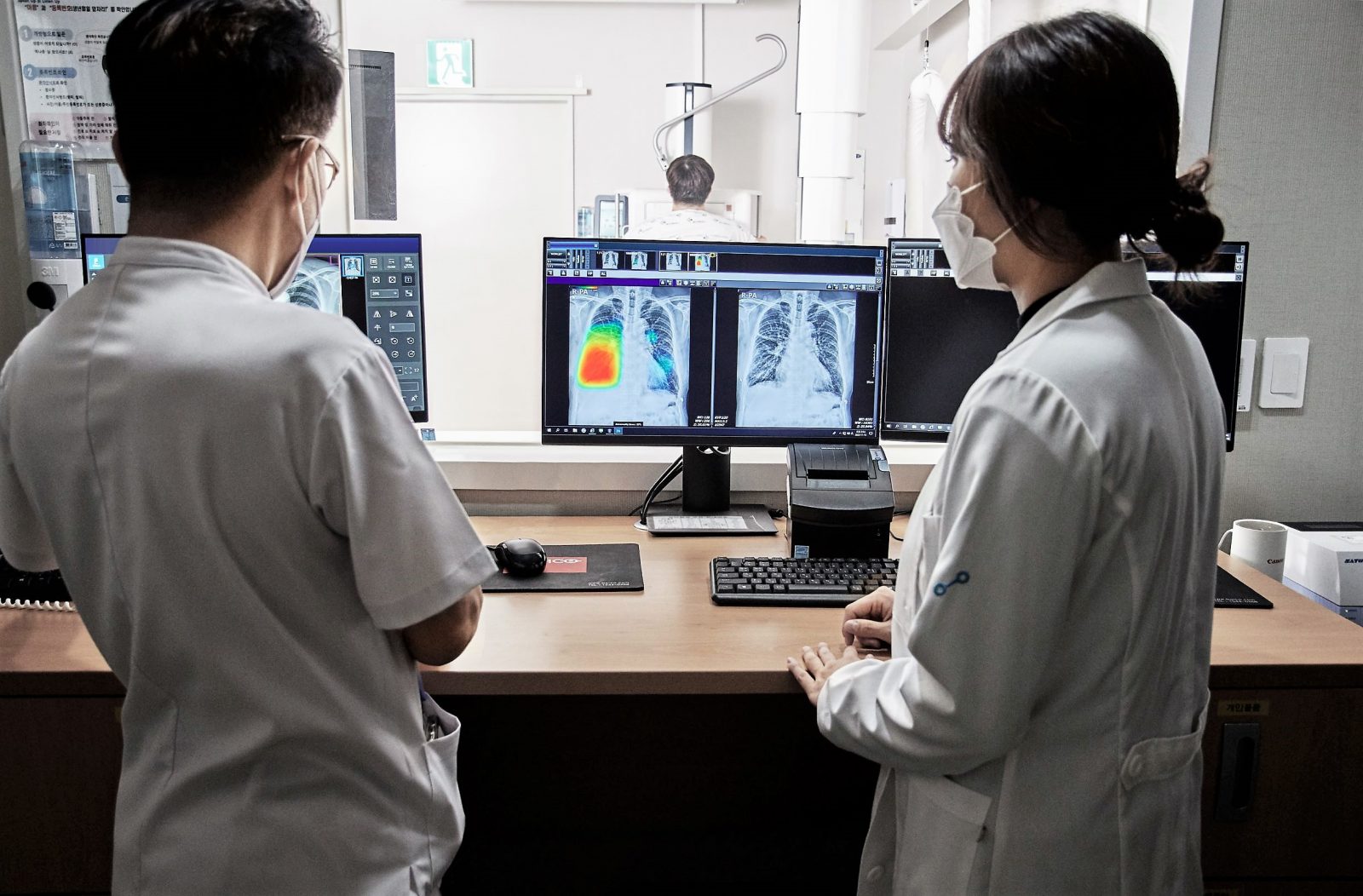 Two people look at X-ray images on a computer screen