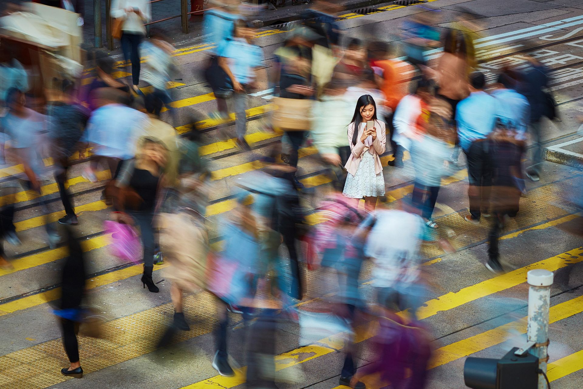 women looking at her smartphone, standing in a crowd