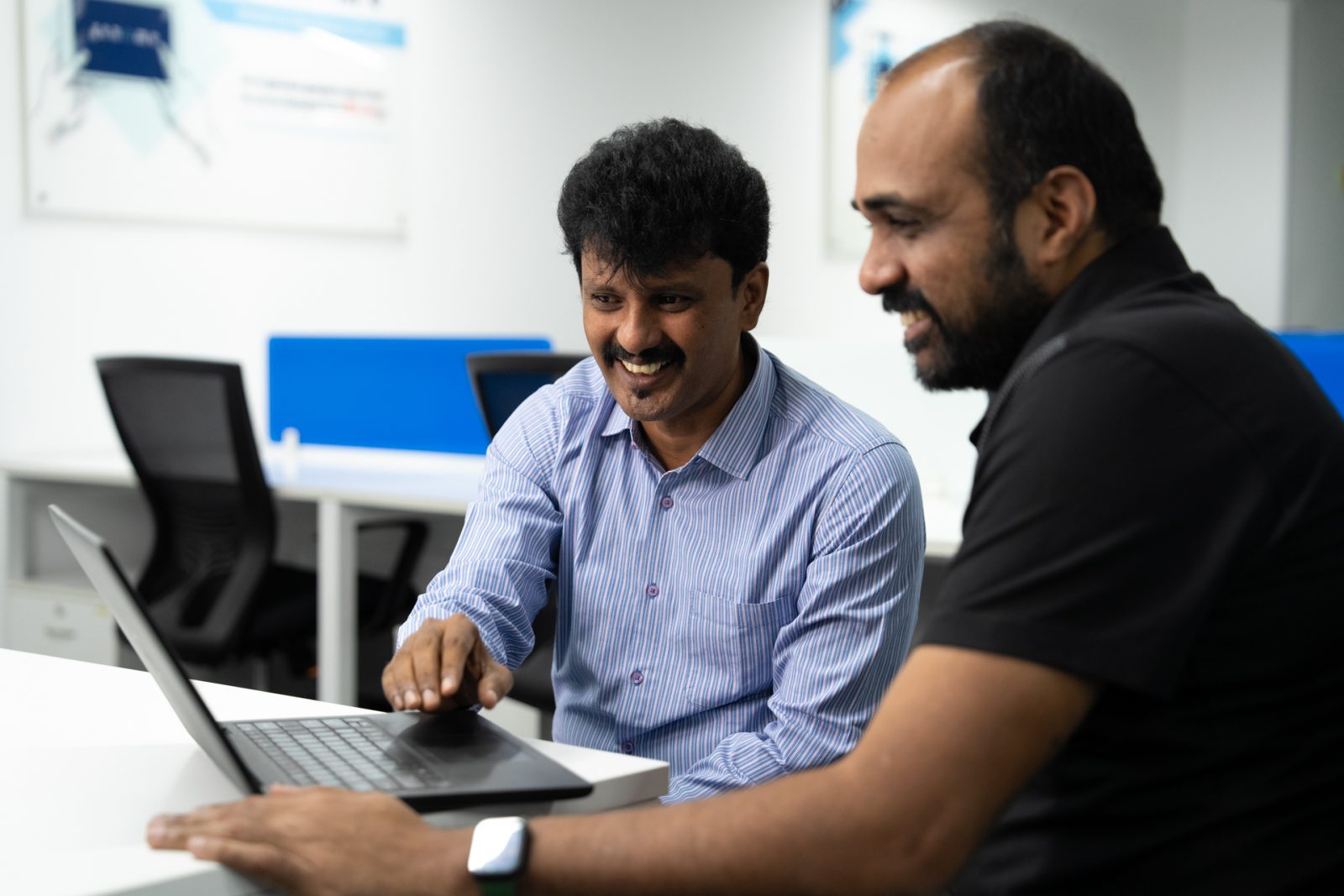 Photo of two men sitting at a desk looking at a computer