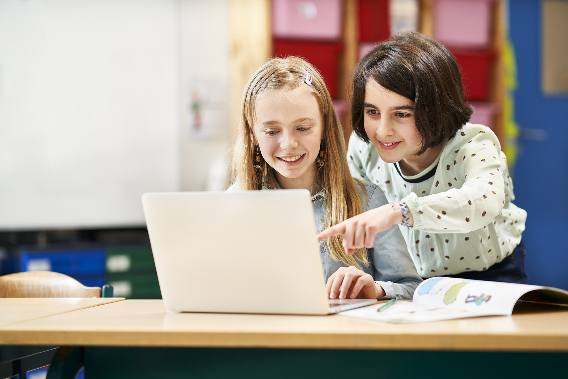 Two children looking at a computer and smiling.