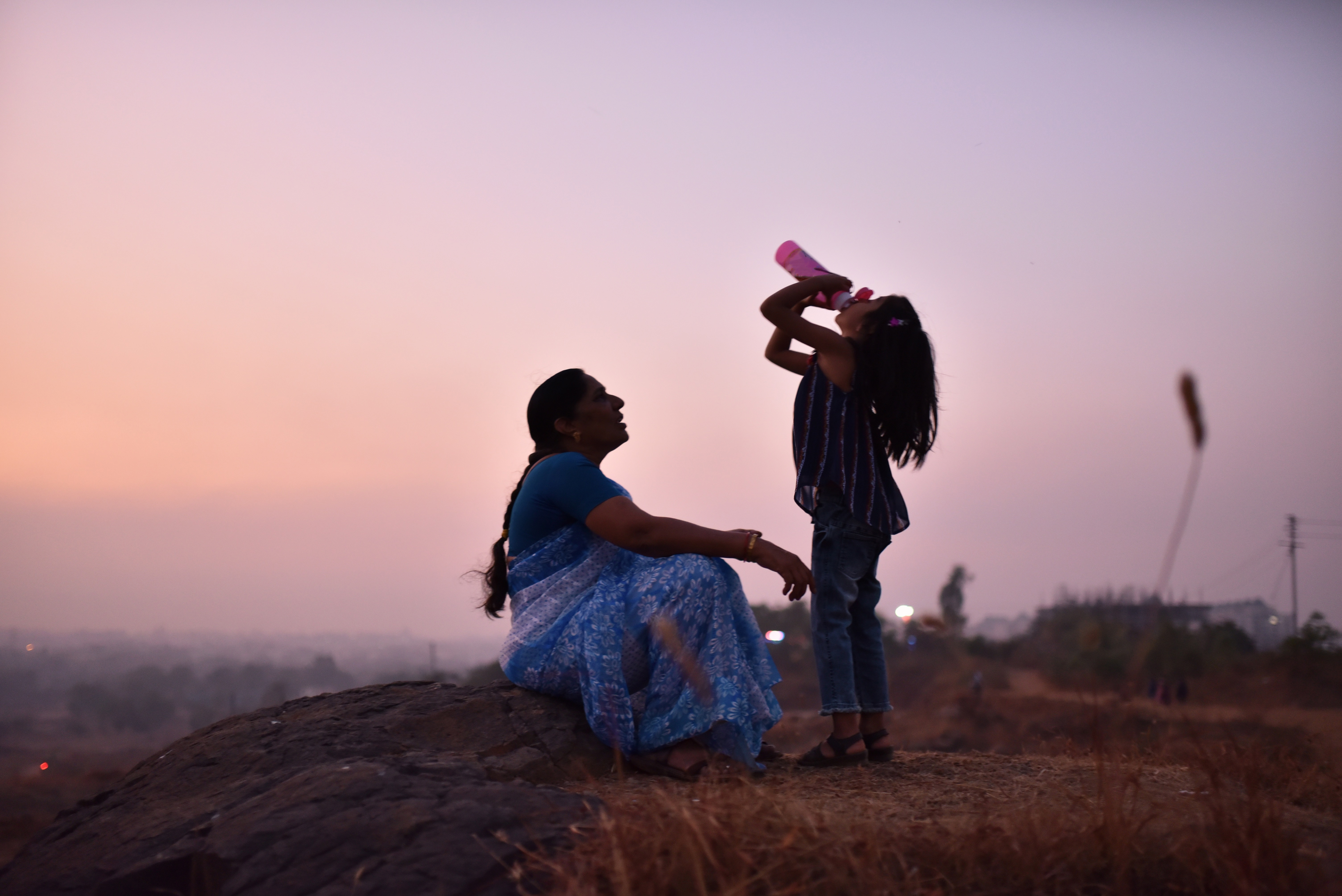 Grandmother and granddaughter drinking water sitting on the hills