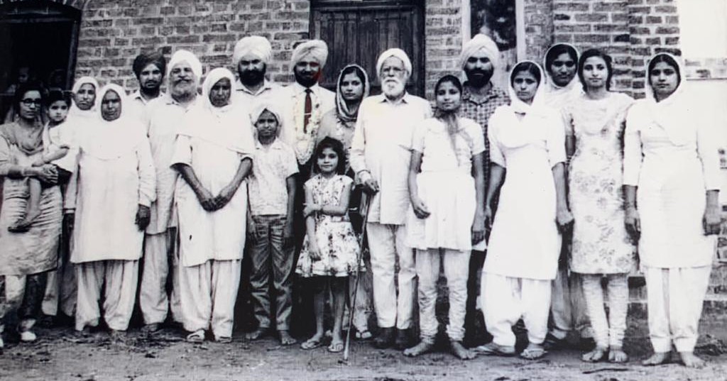 A black and white photo of a group of people standing in front of a house