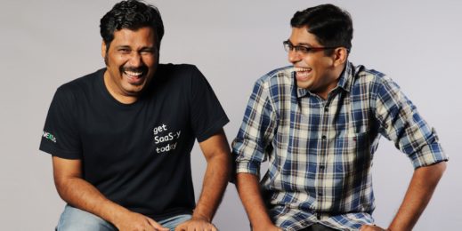 Photo of two men sitting on a bench and laughing