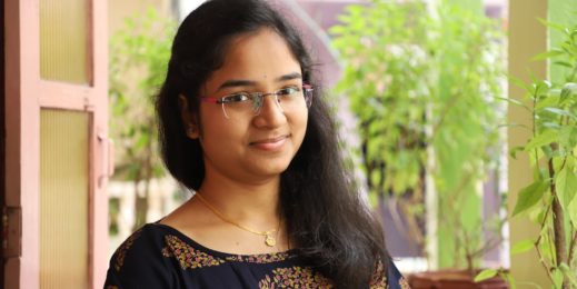 Photo of a girl smiling at the camera with potted plants in the background