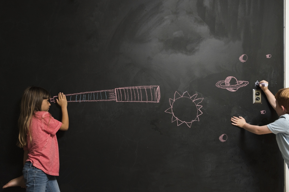 Photo of two kids doodling on a blackboard