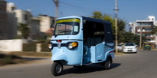 Photo of a blue-colored autorickshaw on a road.