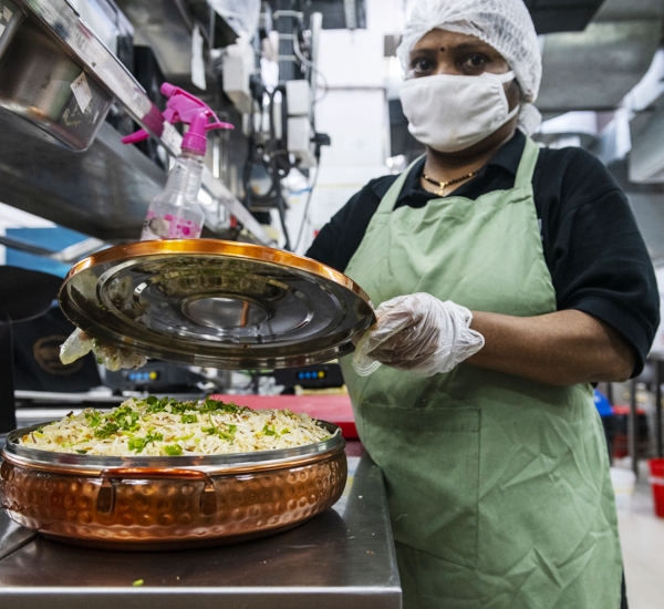 Photo of a female cook showing off a utensil filled with rice based dish