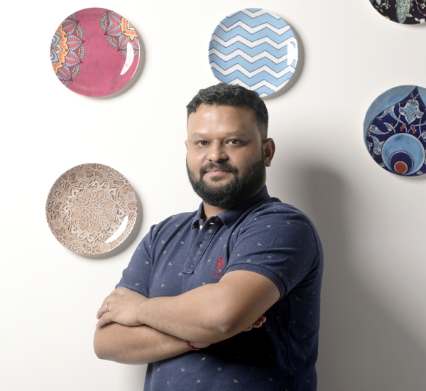 Photo of a man smiling at the camera with wall plates in the background