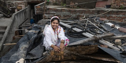 a woman sitting on the roof of her tin shack home displaying a low-cost solution for keeping her house cool