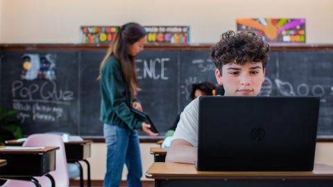 kid in a classroom studying on a laptop