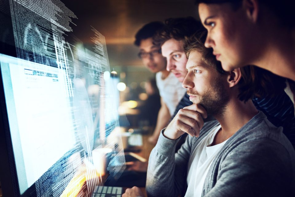 Shot of a group of programmers working on a computer code at night