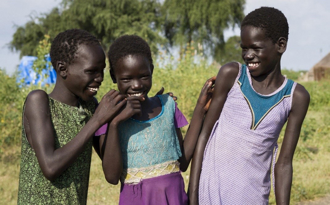 Three young girls wearing dresses laughing