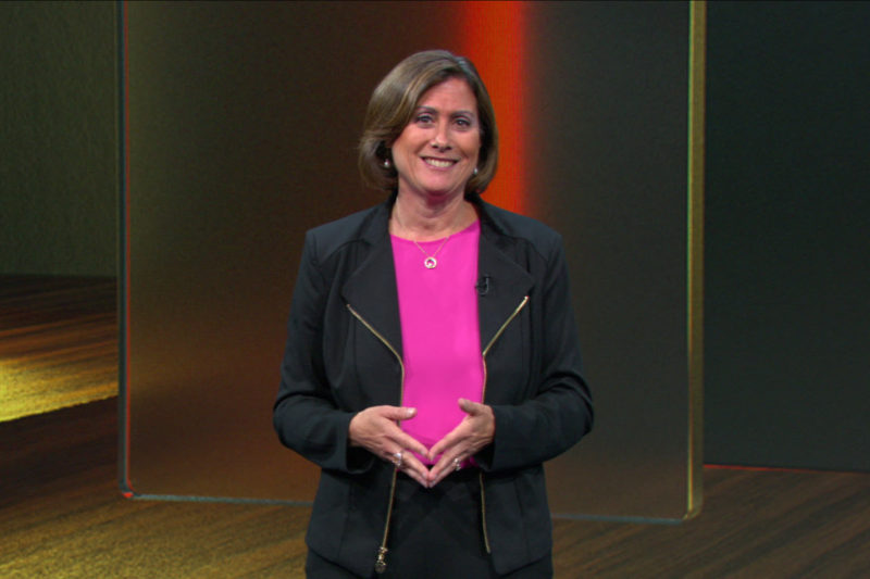 A woman stands on stage speaking.