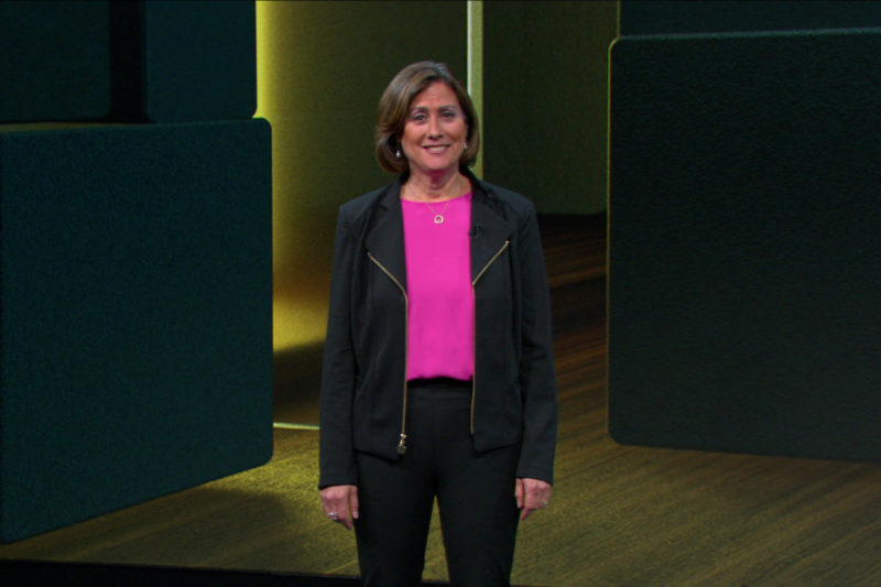 A woman stands on stage speaking.