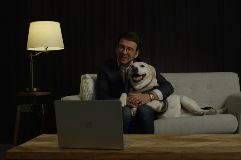 A man sits on a couch with a dog.