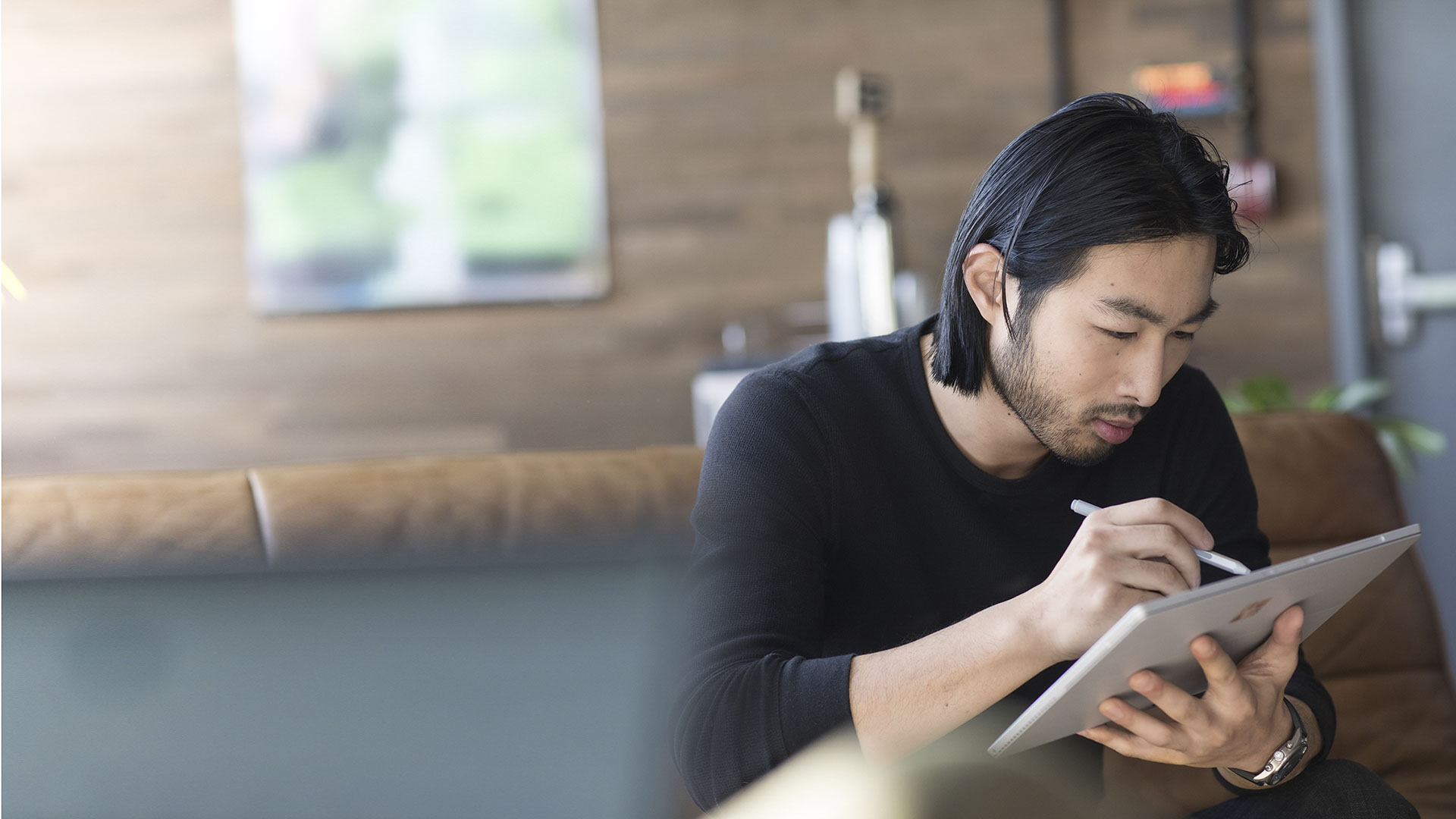 Male holding a Surface with one hand and using a Surface Pen with another