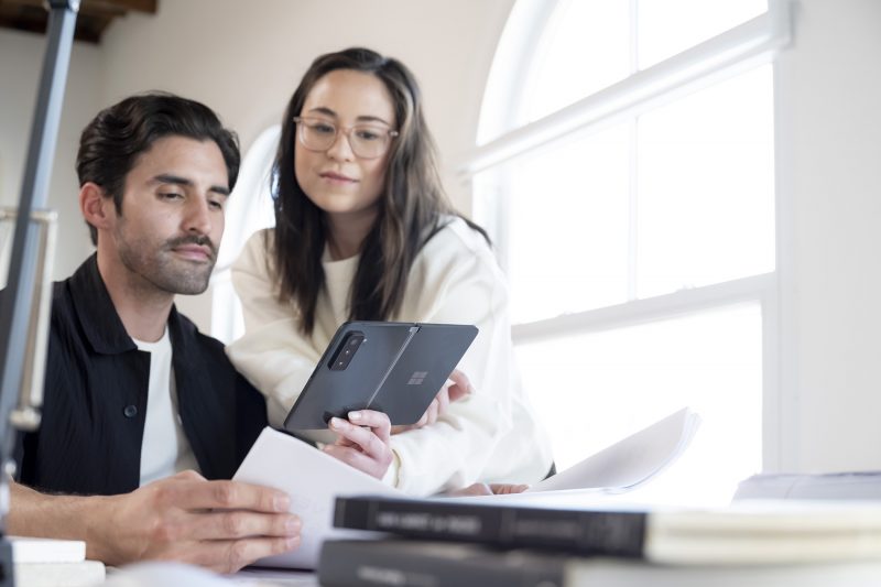 A man and a woman using a Surface Duo 2 phone