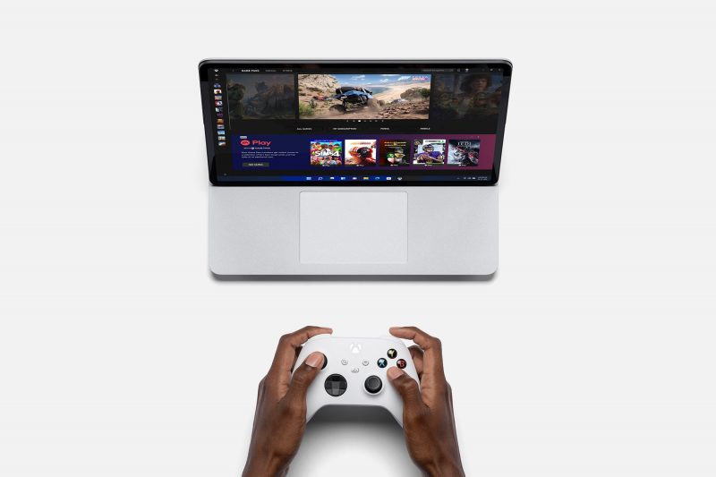 A person playing a game on a Surface laptop using a Xbox controller