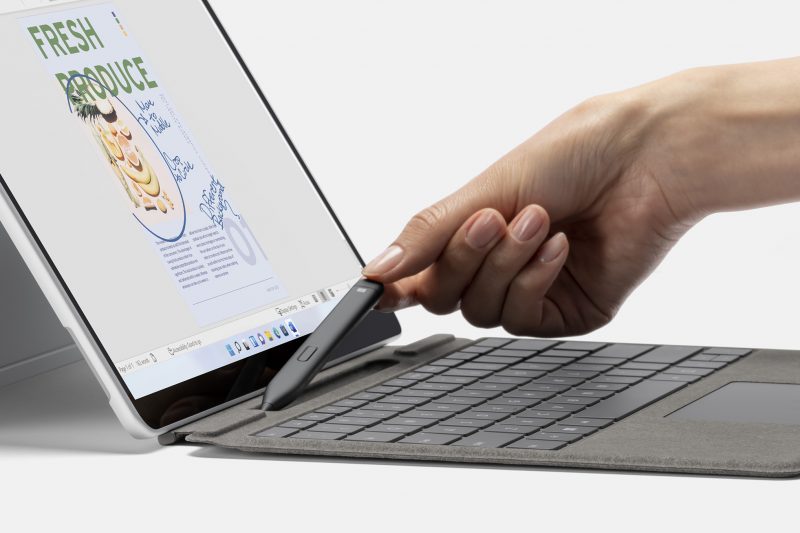 A person holding a Slim Pen 2 next to a Surface Pro 8