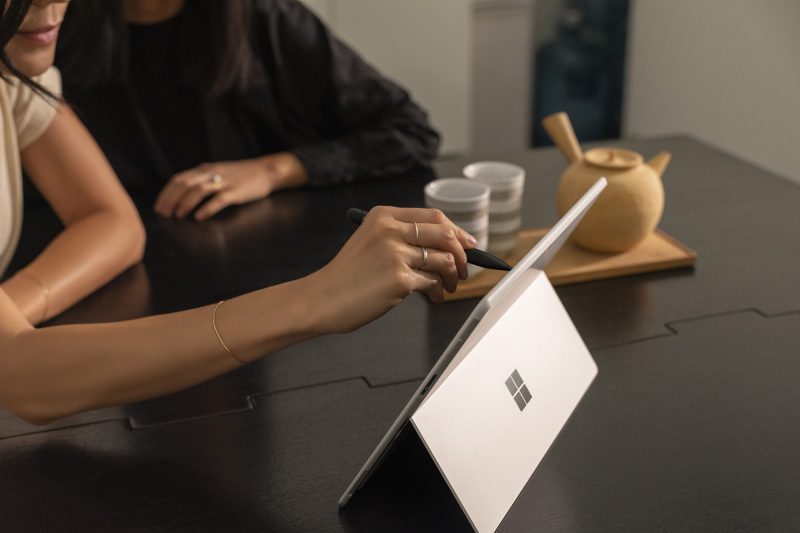 Two people looking at a Surface Pro X device