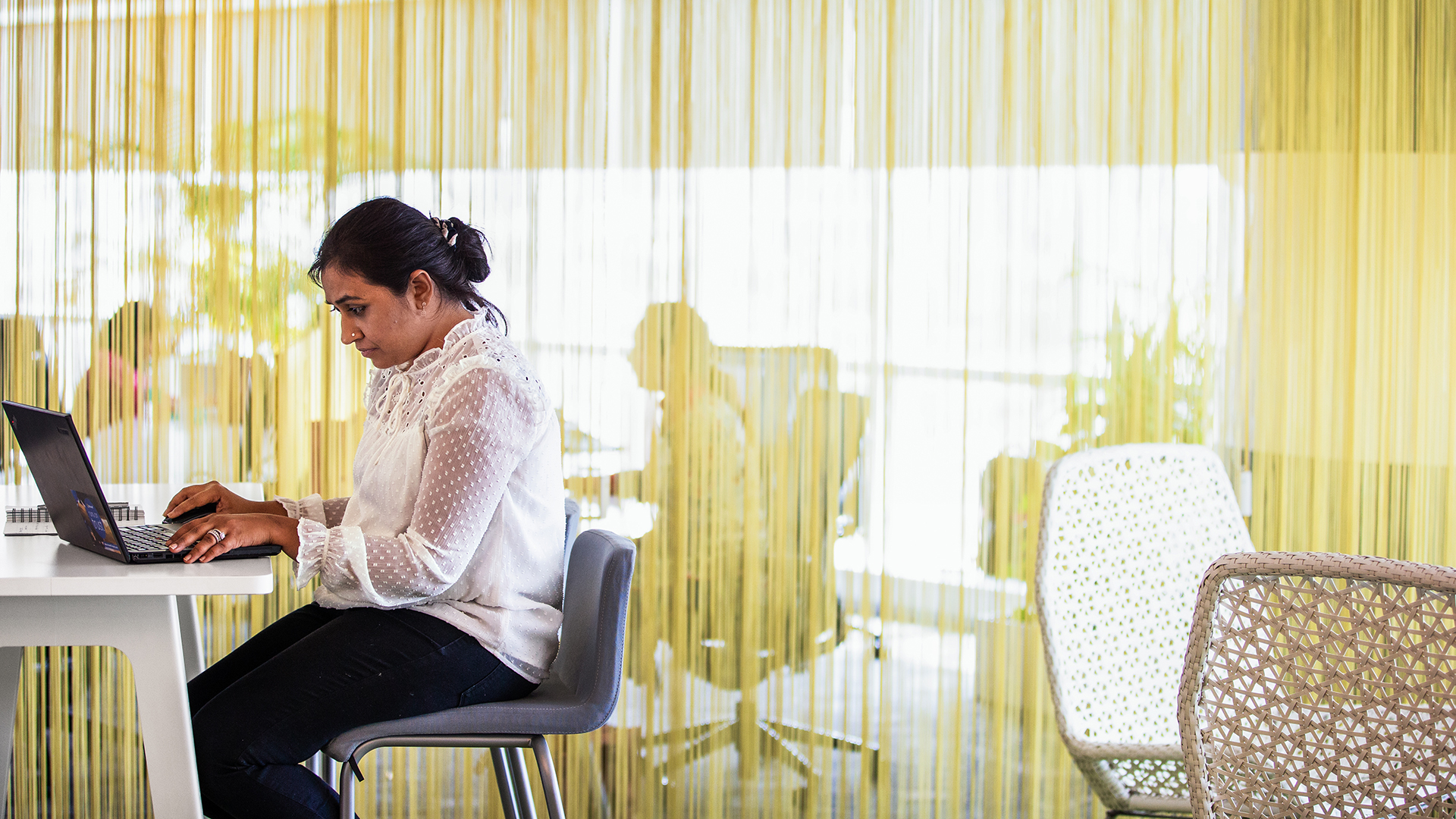 A woman sits at a desk with a laptop