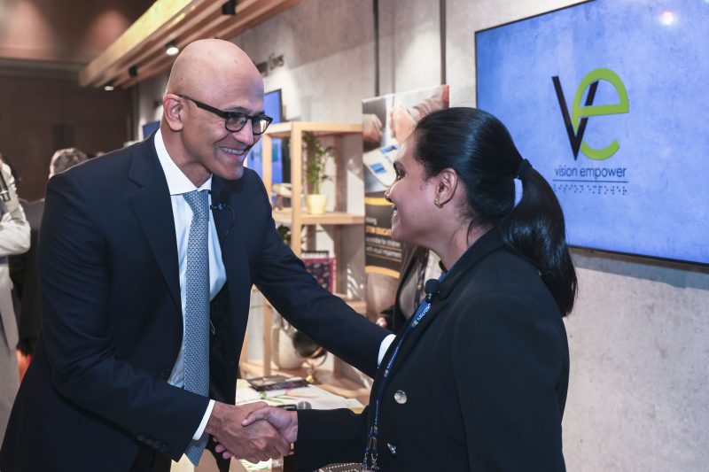 A man and a woman shaking hands with the words vision empower on the display behind them