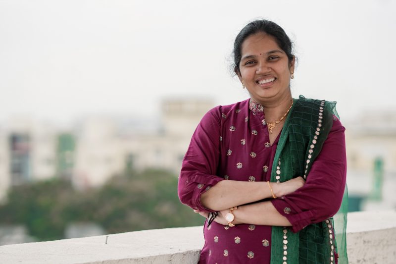 a woman wearing a maroon dress smiling at the camera