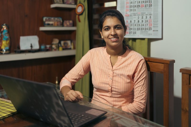 A woman sitting on a dining table and working on a laptop