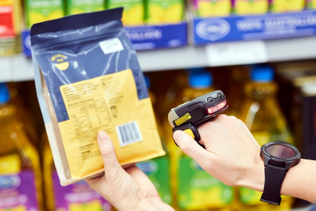 A retail worker using a hand held scanner to check a barcode.