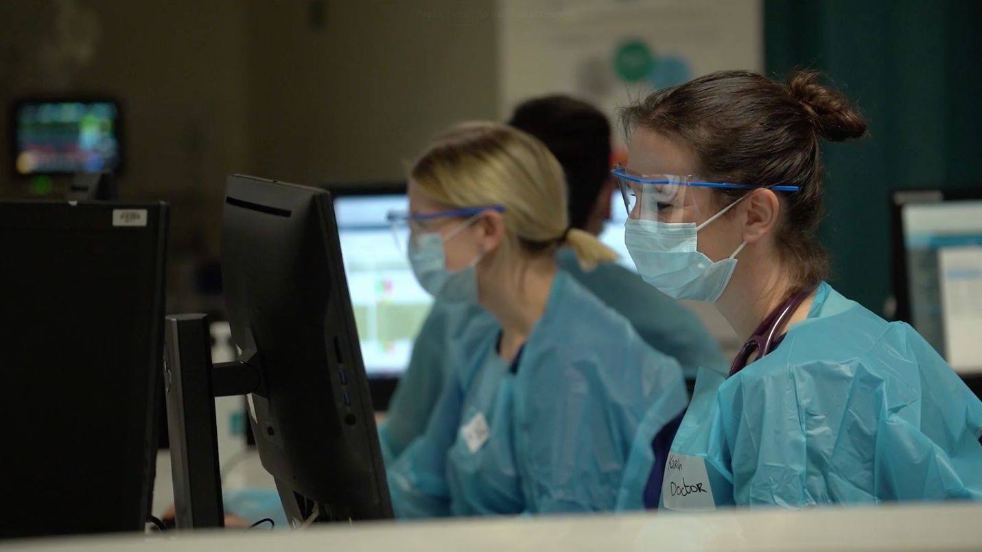 Hospital staff in safety gear working by the computers