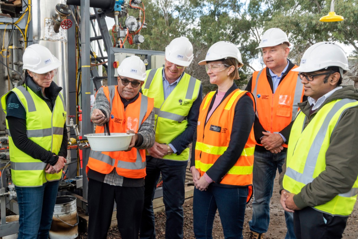 Group of adults in safety workwear inspecting a waste technology demonstration