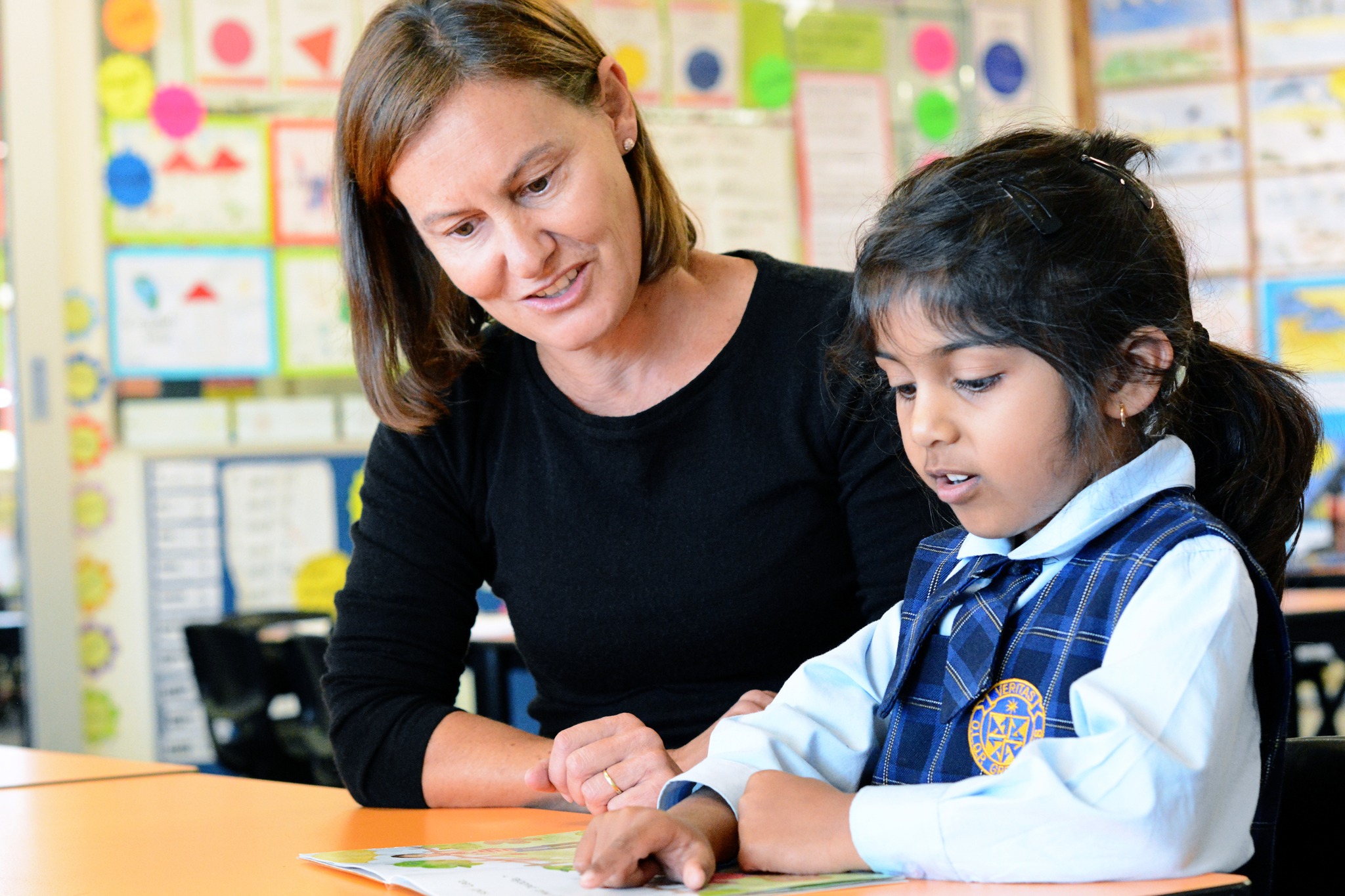 Female school teacher teaching a young female school student