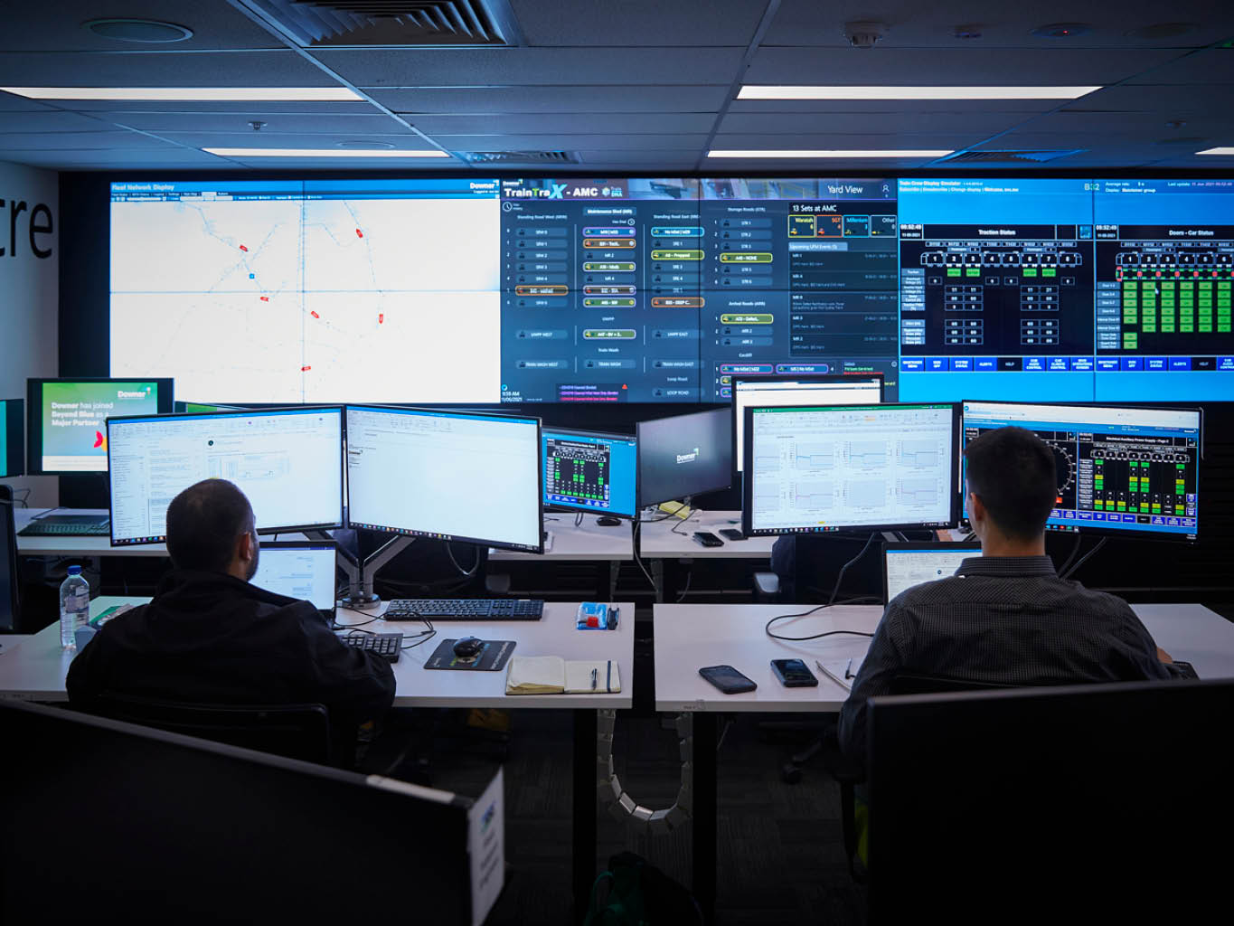 Two adults sitting in a room filled with screens