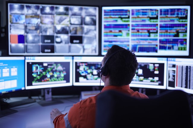 Man sitting infront of a room filled with computer screens