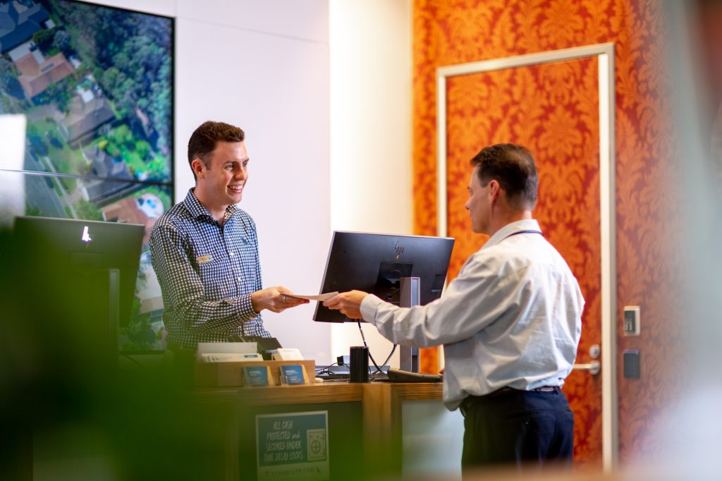 Male customer handing over card to bank service rep