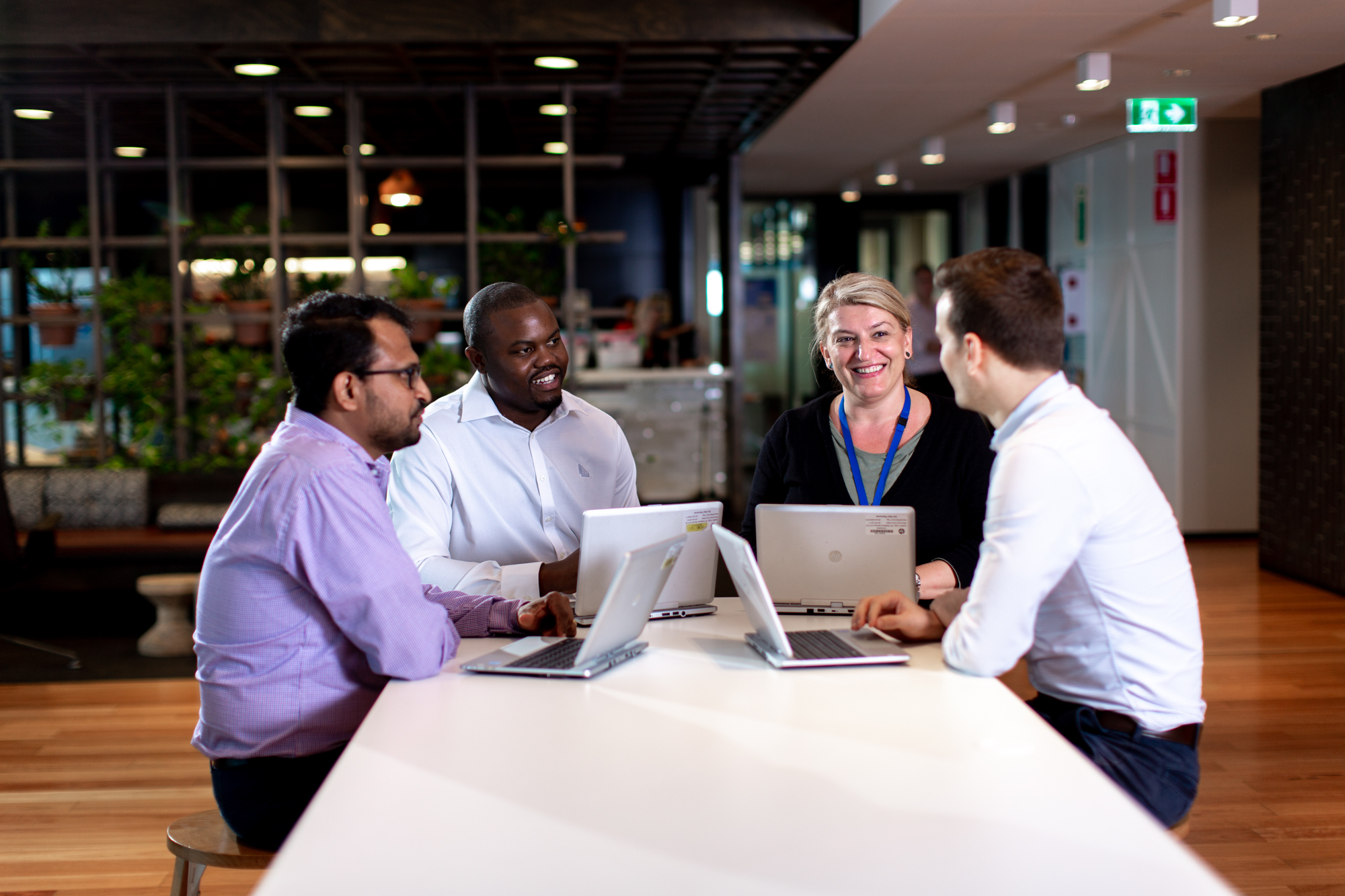 Group of adult workers sitting around a table with their laptops